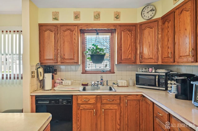 kitchen with black dishwasher, light countertops, a sink, and stainless steel microwave