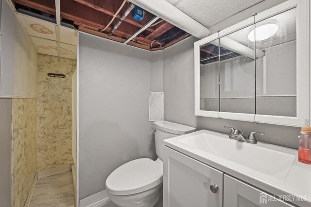 bathroom featuring vanity, toilet, baseboards, and marble finish floor