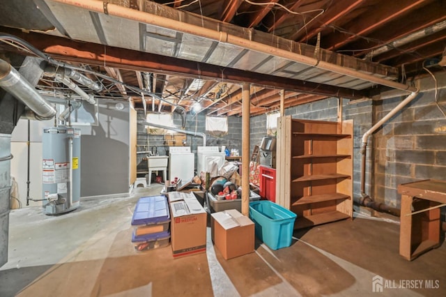 unfinished below grade area featuring gas water heater, washer and clothes dryer, and a sink