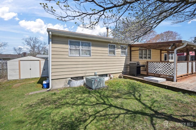 back of house featuring a lawn, an outbuilding, fence, a shed, and a wooden deck