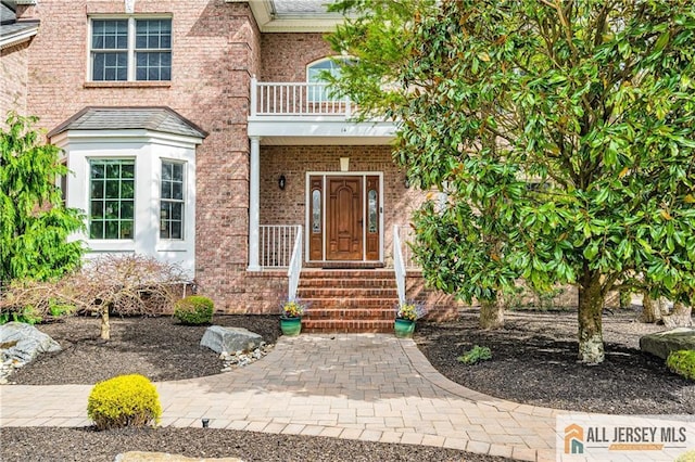 entrance to property with a balcony and brick siding