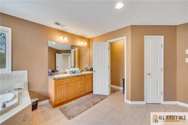 bathroom featuring a bath, double vanity, baseboards, and tile patterned flooring