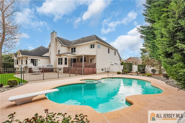 view of swimming pool with a patio area, fence, a diving board, and a pool with connected hot tub