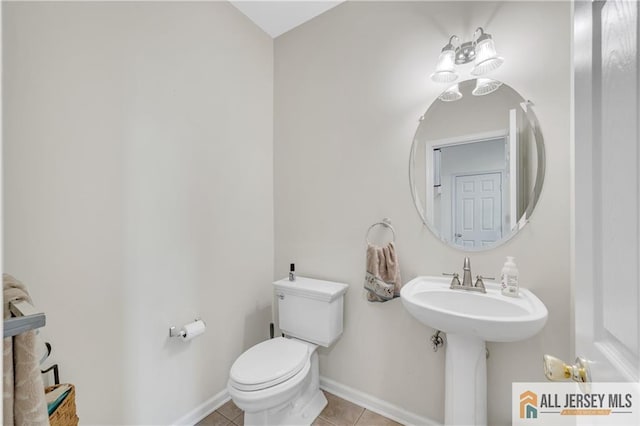 half bath featuring tile patterned floors, toilet, and baseboards