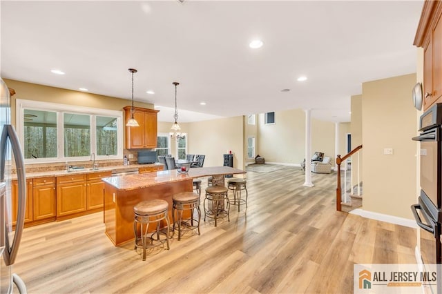 kitchen featuring a kitchen island, light wood finished floors, oven, a kitchen bar, and freestanding refrigerator