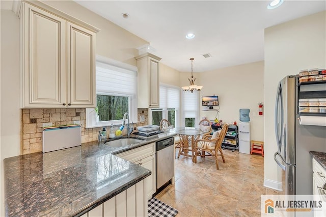 kitchen with stainless steel appliances, a sink, cream cabinetry, a chandelier, and recessed lighting