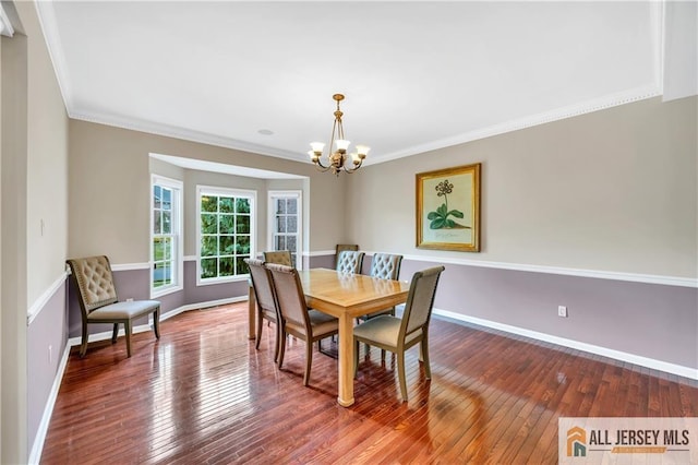 dining room with a chandelier, baseboards, wood-type flooring, and crown molding