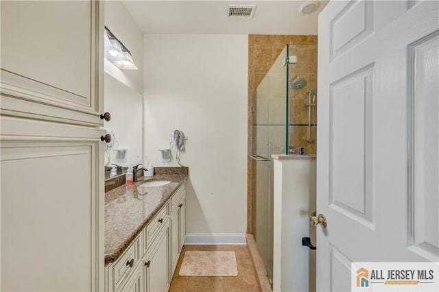 full bathroom with a tile shower, vanity, and baseboards