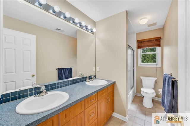 bathroom featuring toilet, tile patterned flooring, double vanity, and baseboards