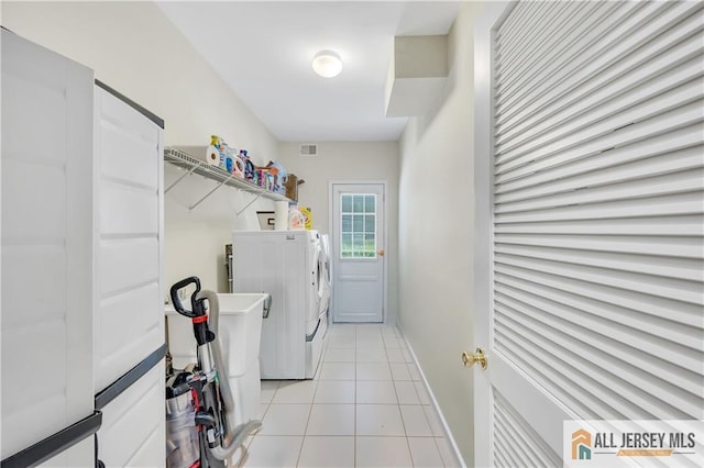 clothes washing area featuring washer and dryer, light tile patterned floors, and baseboards