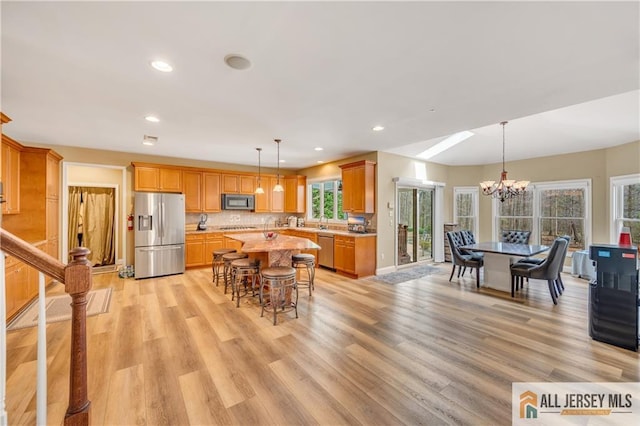 dining room with a chandelier, light wood finished floors, recessed lighting, and baseboards