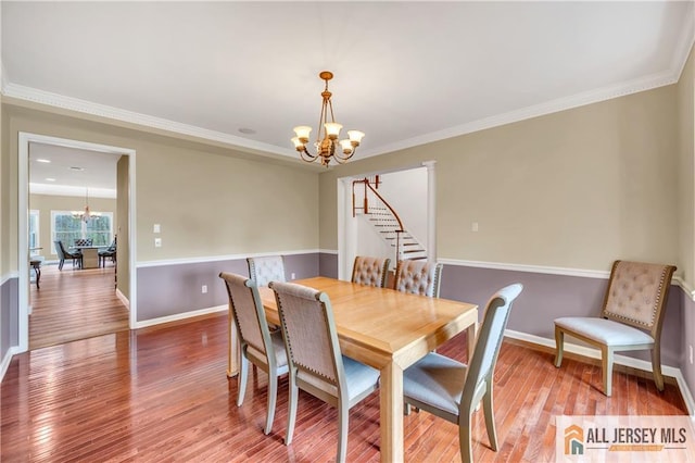 dining area featuring a chandelier, wood finished floors, baseboards, and crown molding