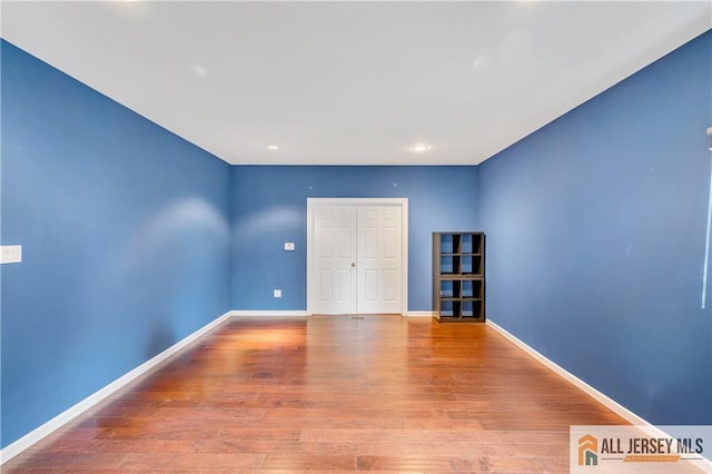 spare room featuring wood finished floors, baseboards, and recessed lighting