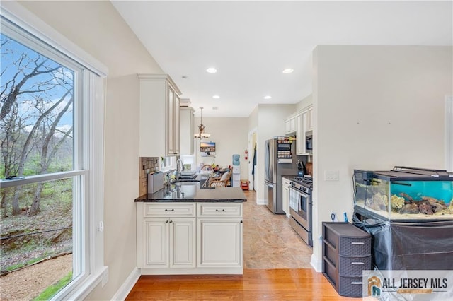kitchen with appliances with stainless steel finishes, healthy amount of natural light, a sink, white cabinetry, and recessed lighting