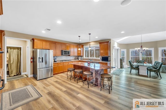 kitchen featuring appliances with stainless steel finishes, a kitchen breakfast bar, healthy amount of natural light, light wood-type flooring, and recessed lighting