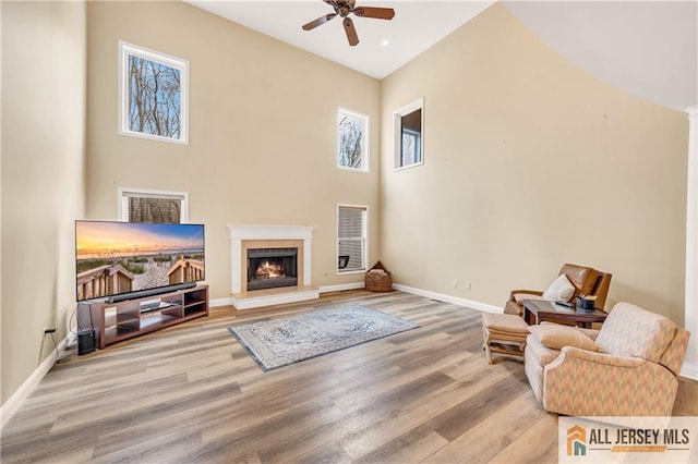 living area featuring a ceiling fan, plenty of natural light, wood finished floors, and baseboards