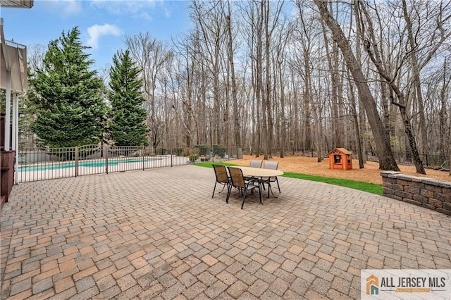 view of patio with fence, outdoor dining space, an outbuilding, and a storage unit