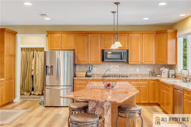kitchen featuring stainless steel appliances, a sink, light wood-style flooring, decorative light fixtures, and recessed lighting