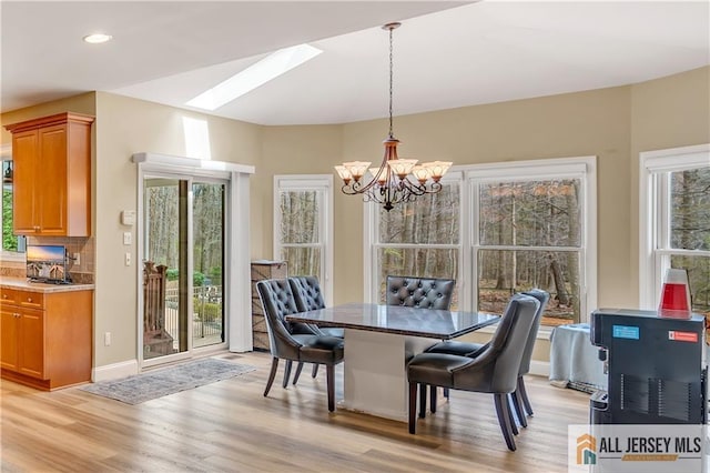 dining room with a chandelier, a skylight, light wood-type flooring, recessed lighting, and baseboards