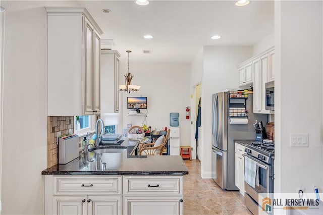 kitchen with appliances with stainless steel finishes, a sink, dark stone counters, pendant lighting, and recessed lighting