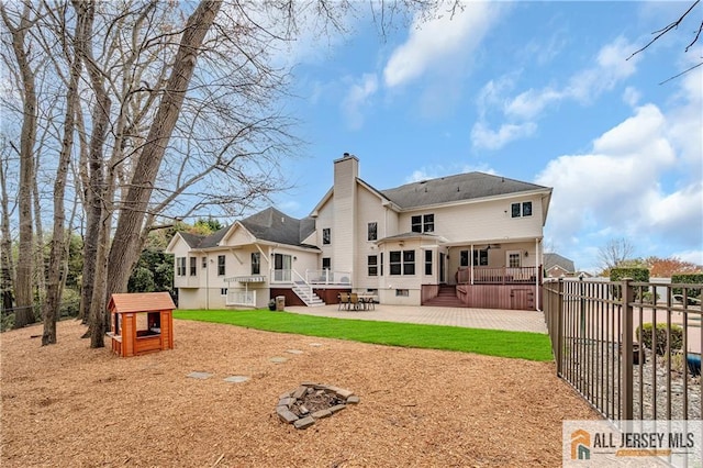 back of house featuring a patio, a chimney, a deck, and fence