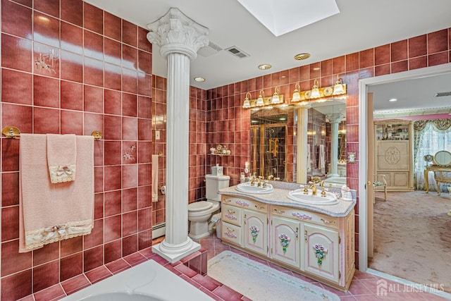 full bathroom featuring decorative columns, tile patterned floors, toilet, tile walls, and double vanity