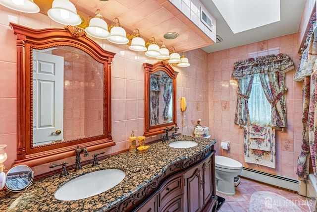 bathroom with baseboard heating, tile walls, toilet, tile patterned floors, and double vanity