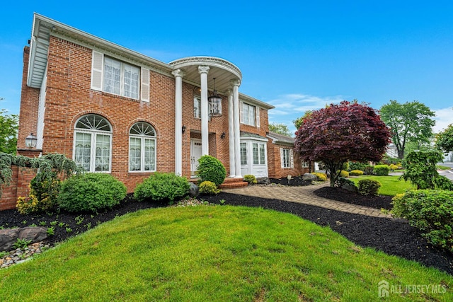 neoclassical home with a front lawn and brick siding
