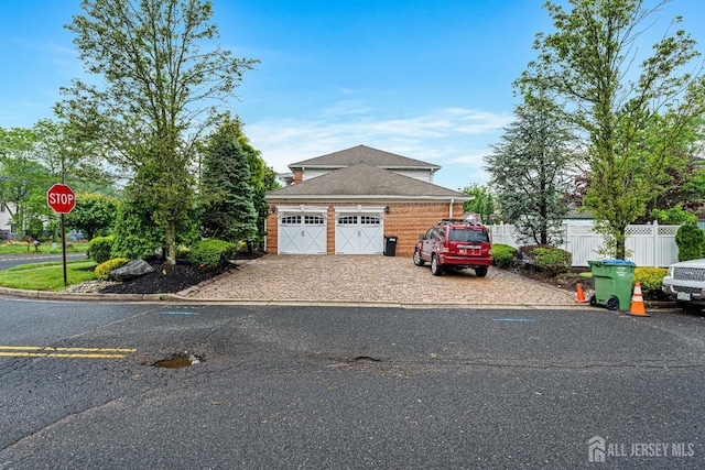view of front of property featuring fence, roof with shingles, and driveway