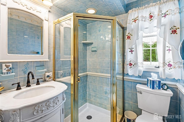 full bath featuring tile walls, a stall shower, vanity, and toilet