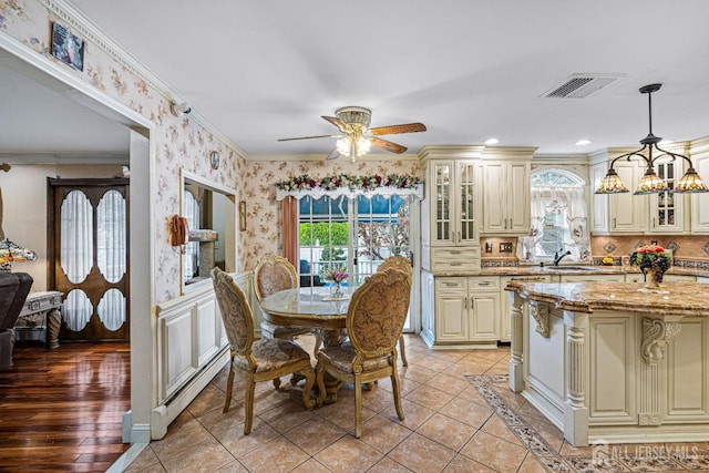 dining area with crown molding, ceiling fan, light tile patterned floors, a baseboard heating unit, and wallpapered walls