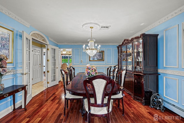 dining room with a decorative wall, a chandelier, dark wood-style flooring, a baseboard heating unit, and french doors