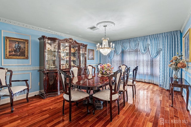 dining room with a chandelier, wood finished floors, wallpapered walls, crown molding, and baseboards