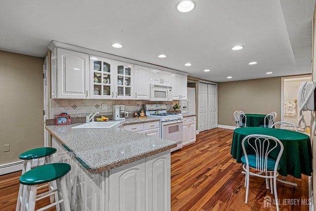 kitchen featuring white appliances, a sink, glass insert cabinets, wood finished floors, and white cabinets