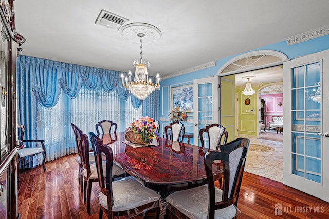 dining area with a chandelier, wood finished floors, and french doors