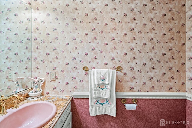 bathroom with wallpapered walls, vanity, and a wainscoted wall