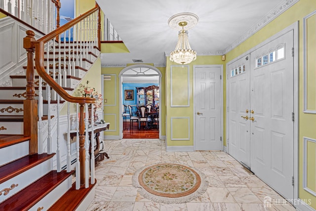 entryway featuring stairway, a chandelier, arched walkways, and light marble finish floors