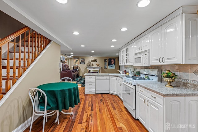 kitchen with white appliances, light wood-style flooring, white cabinetry, recessed lighting, and a sink