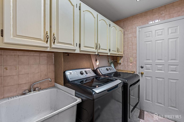 clothes washing area with washing machine and clothes dryer, cabinet space, tile walls, and tile patterned flooring