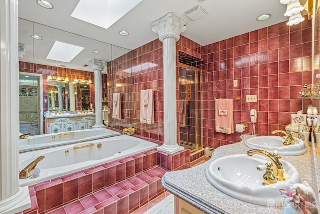 full bathroom with a skylight, tile walls, ornate columns, a jetted tub, and vanity