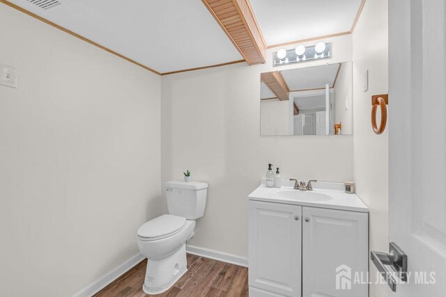 bathroom with wood-type flooring, vanity, toilet, and ornamental molding