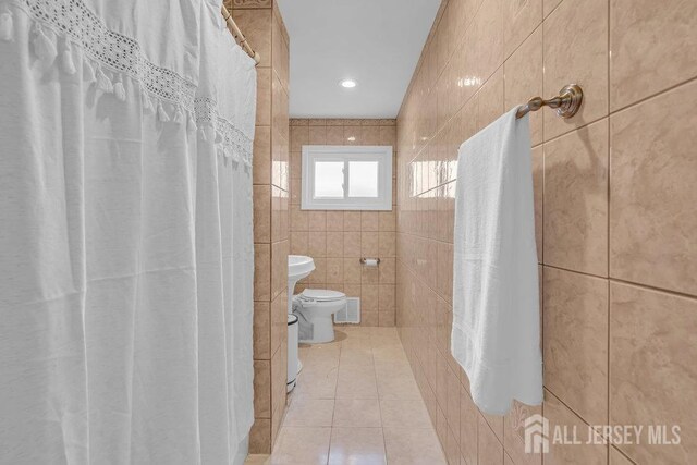 bathroom featuring tile patterned flooring, a shower with shower curtain, tile walls, and toilet