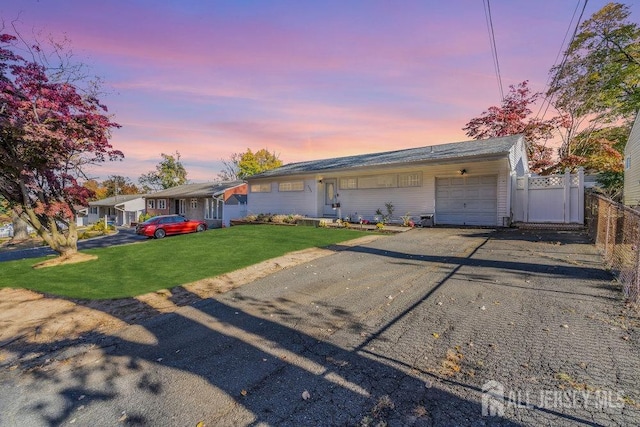 ranch-style house with a garage and a lawn