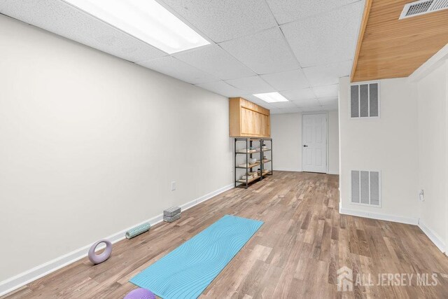 workout room featuring hardwood / wood-style floors and a paneled ceiling