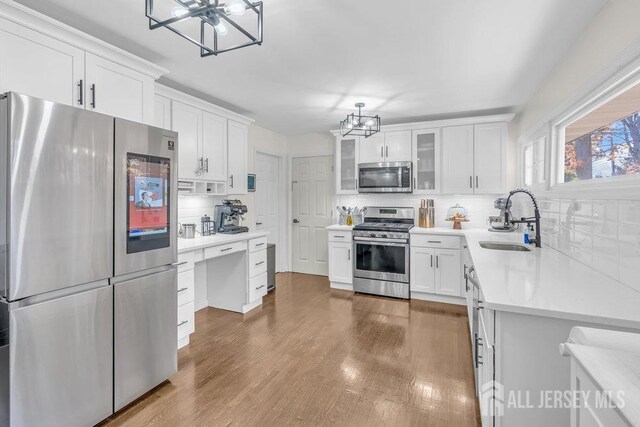 kitchen featuring white cabinetry, sink, dark wood-type flooring, stainless steel appliances, and backsplash