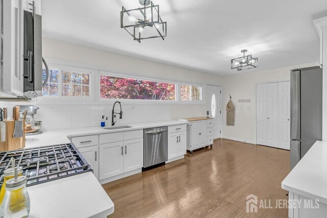 kitchen with pendant lighting, sink, appliances with stainless steel finishes, tasteful backsplash, and white cabinetry