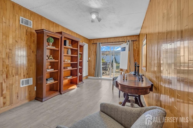 sitting room with a textured ceiling and wood walls