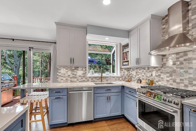 107 Sayre Dr, Plainsboro, NJ 08540 - kitchen featuring wall chimney range hood, stainless steel appliances, tasteful backsplash, light wood-style flooring, and gray cabinets