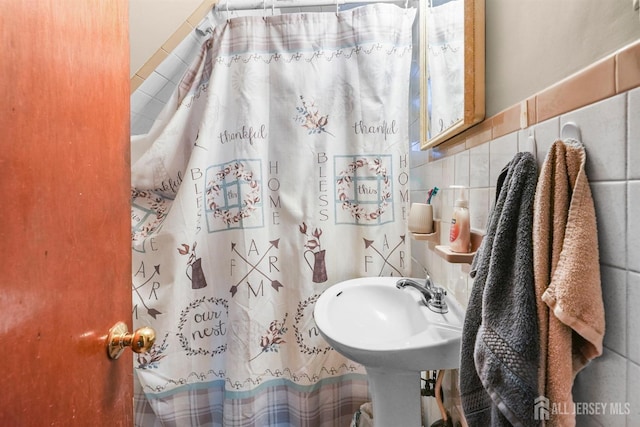 full bath featuring a shower with curtain, a sink, and tile walls