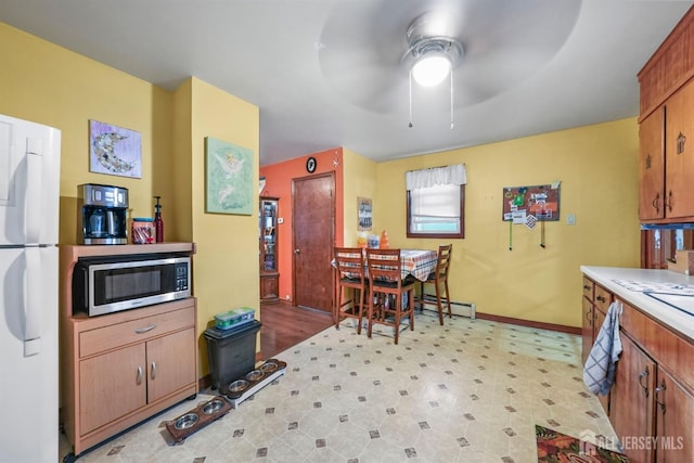 kitchen featuring light floors, light countertops, stainless steel microwave, freestanding refrigerator, and baseboards